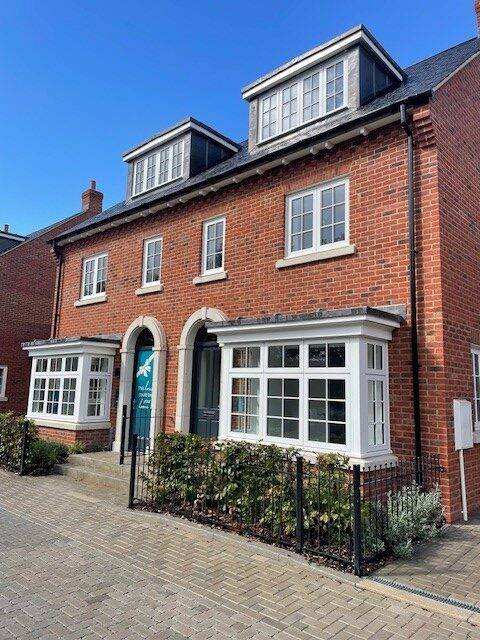 New build property by Croudace Homes in Reading showing timber windows with natural finish, set within brick walls, white frames and large glazed panes allowing views through into interior